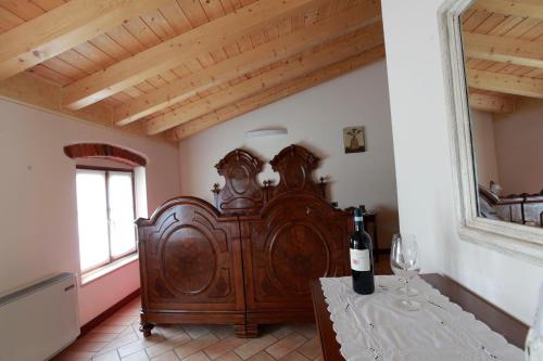 Zimmer mit einem großen Holzbett und einer Flasche Wein in der Unterkunft Locanda da Bepi in Marano di Valpolicella