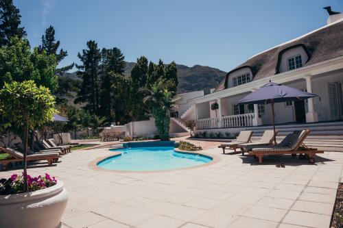 a patio with chairs and a pool and a house at Mirabelle Guesthouse in Franschhoek