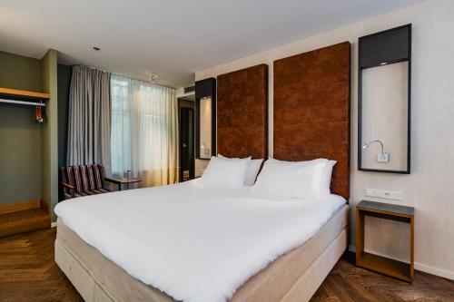 ein großes weißes Bett in einem Hotelzimmer in der Unterkunft Hotel De Hallen in Amsterdam