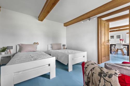 a white bedroom with two beds and a chair at Ferienwohnung Hohe Luft EG in Steinberg