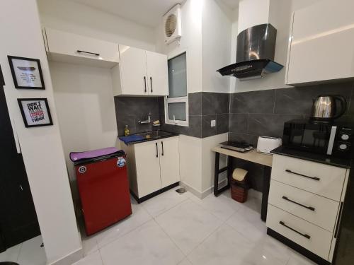 a small kitchen with white cabinets and a red refrigerator at 1 Bed Modern Apartment, Pool, Gym, Cinema in Lahore