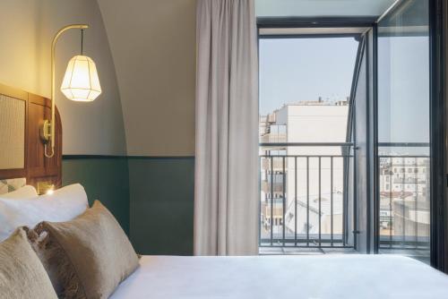 クリシーにあるvoco Paris - Porte de Clichy, an IHG Hotelのベッドと大きな窓が備わるホテルルームです。