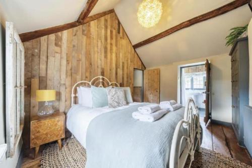 a bedroom with a large white bed and wooden walls at 18th Cent Cottage - 5min drive Soho Farmhouse in Ledwell