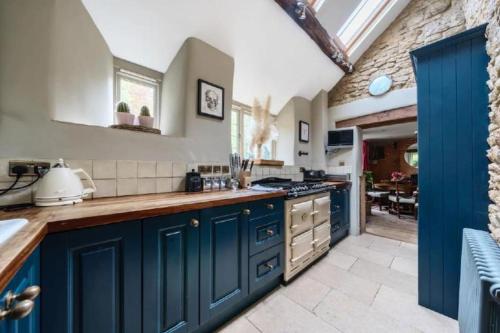 a kitchen with blue cabinets and a counter top at 18th Cent Cottage - 5min drive Soho Farmhouse in Ledwell
