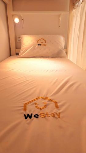 uma cama branca com uma placa que diz wii nela em WeStay Ladies Hostel em Dubai