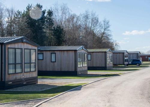 a row of wooden houses in a parking lot at Appletree Holiday Park 