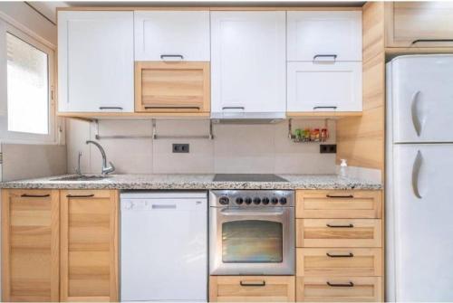 a kitchen with white appliances and wooden cabinets at Piso turístico hasta 3 dormitorios "La Gimena" in Orihuela