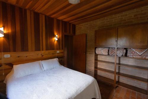 a bedroom with a white bed and wooden cabinets at Chalés Recanto da Mantiqueira in Gonçalves