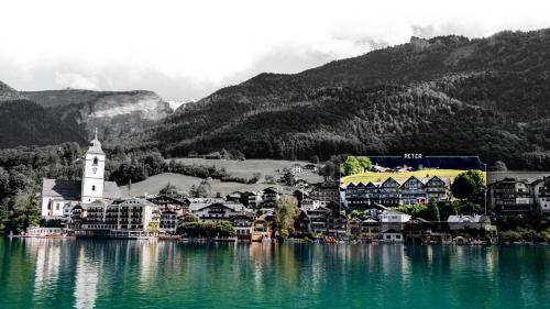 a town on the shore of a lake with mountains at Hotel Peter in St. Wolfgang