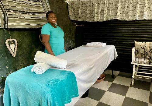 a woman standing next to a bed in a room at Victoria Falls Backpackers Lodge- Camp Sites in Victoria Falls