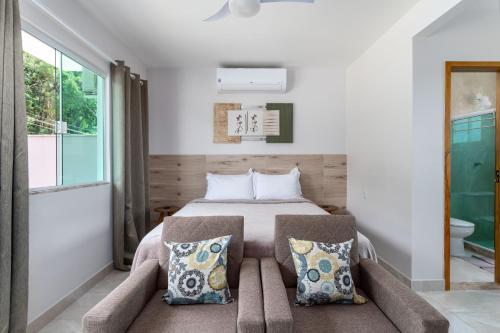 ein Schlafzimmer mit einem Bett mit einem Sofa und einem Fenster in der Unterkunft NStudio Itaipuaçu - Garagem Privativa - Localizado a 1000m da praia in Maricá