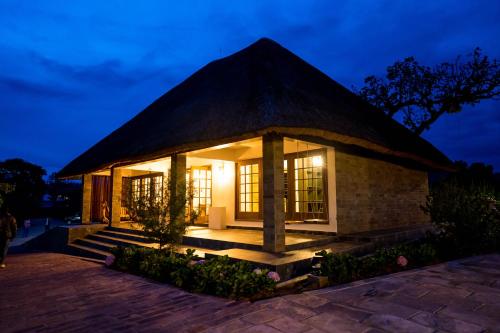 a small building with a thatched roof at night at Tabebuia Spa and Safari Resort in Fort Portal
