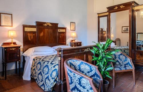 a bedroom with a bed and two chairs at Villa Pitiana in Donnini