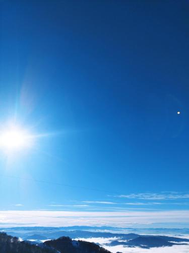 a clear blue sky with the sun above the mountains at President Kop Apartman 106 in Kopaonik
