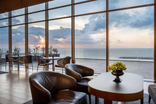 a room with chairs and tables and a large window at Hilton Tel Aviv Hotel in Tel Aviv