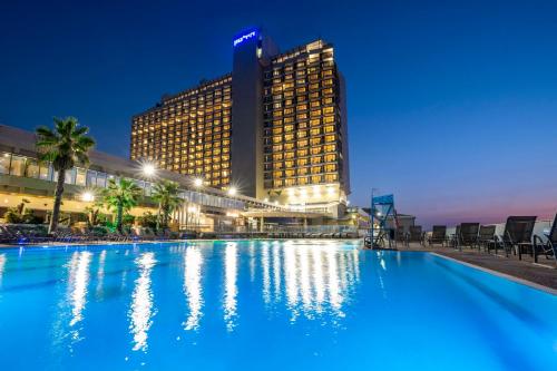 a large swimming pool in front of a tall building at Hilton Tel Aviv Hotel in Tel Aviv