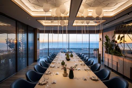 a long dining room with a long table and chairs at Hilton Tel Aviv Hotel in Tel Aviv