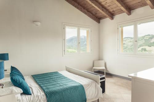 a white bedroom with two beds and two windows at Casa Ruspiano in Vergato