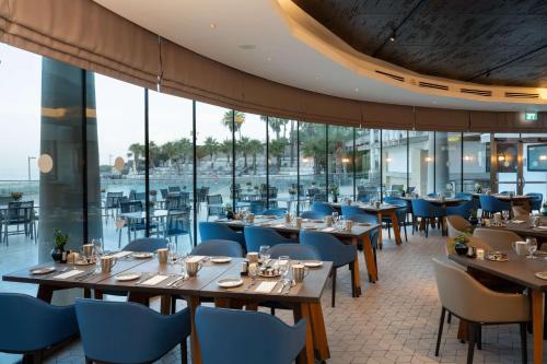 a restaurant with wooden tables and blue chairs at Hilton Tel Aviv Hotel in Tel Aviv
