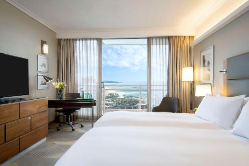 a hotel room with a bed and a desk and a window at Hilton Tel Aviv Hotel in Tel Aviv