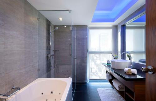 a bathroom with a tub and a shower and a sink at Hilton Tel Aviv Hotel in Tel Aviv