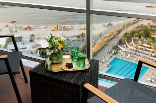a table with a tray of food and flowers and a view of the beach at Hilton Tel Aviv Hotel in Tel Aviv