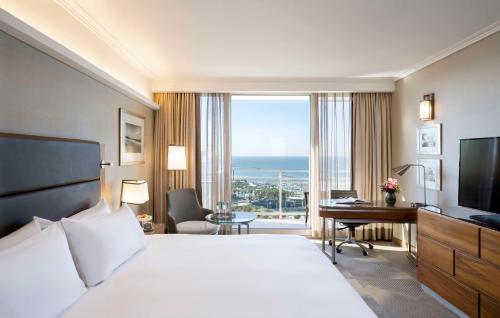 a hotel room with a bed and a desk and a television at Hilton Tel Aviv Hotel in Tel Aviv