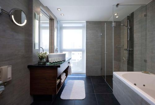 a bathroom with a tub and a shower and a sink at Hilton Tel Aviv Hotel in Tel Aviv