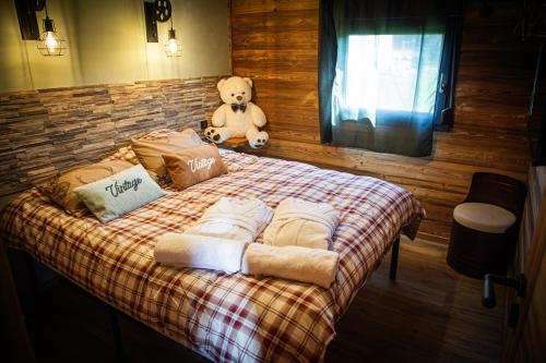 a teddy bear sitting on a bed in a room at Domaine de la vôge & chalets et spa in Xertigny