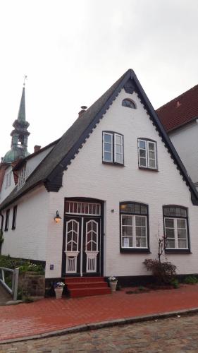 a white house with a church steeple in the background at Strandläufer in Kappeln
