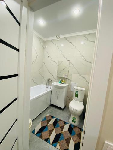 a white bathroom with a toilet and a bath tub at 1кмн Квартира по проспекту Республика 30 in Astana