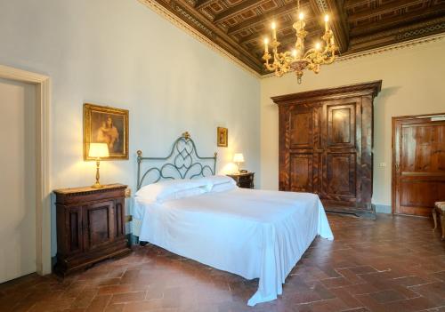 a bedroom with a white bed and a chandelier at Villa Pitiana in Donnini