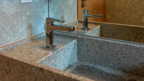 um lavatório de casa de banho com duas torneiras e um espelho em Salinas Premium Resort em Salinópolis