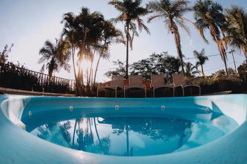 a swimming pool with chairs and palm trees at Itatiba Orion Hotel in Itatiba