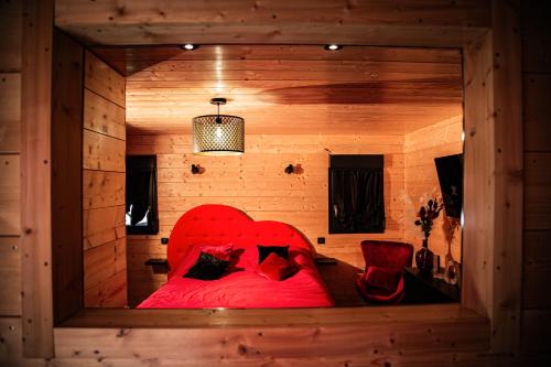 een slaapkamer met een rood bed in een houten kamer bij Domaine de la vôge & chalets et spa in Xertigny