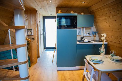 een keuken met een blauwe koelkast en een tafel bij Domaine de la vôge & chalets et spa in Xertigny