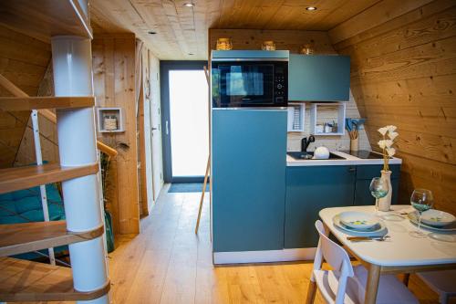 a kitchen with a blue refrigerator and a table at Domaine de la vôge & chalets et spa in Xertigny