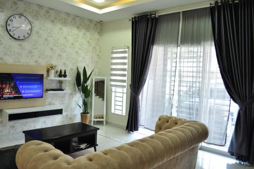 a living room with a couch and a clock on the wall at De’ Nuhir Homestay Teluk Senangin in Kampong Batu Tiga