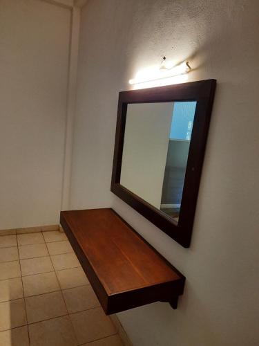 a mirror hanging on a wall with a wooden shelf at Lake View Villa in Mirissa