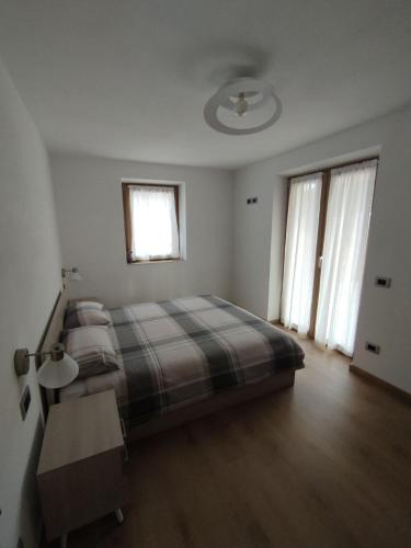 a bedroom with a bed and two windows at Nuovo Appartamento con Giardino in Folgaria