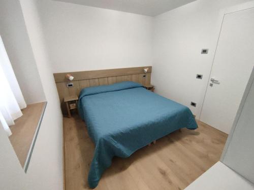 a small bedroom with a bed with a blue blanket at Nuovo Appartamento con Giardino in Folgaria