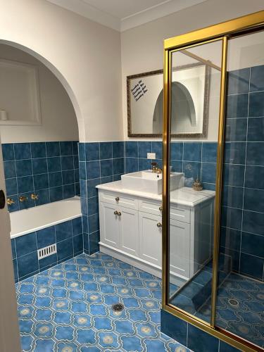 y baño con azulejos azules, lavabo y ducha. en Palm Beach Bed & Breakfast, en Palm Beach