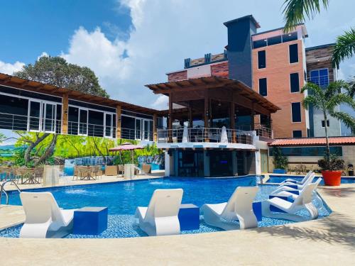 basen z białymi krzesłami i budynek w obiekcie Halibut Hotel w mieście La Romana