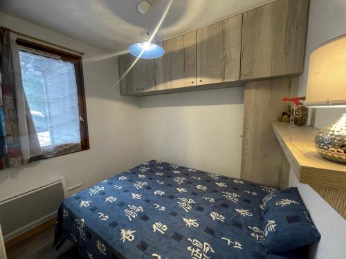 - une petite chambre avec un lit et une couverture bleue dans l'établissement Cotagnes 1 - Appartement proche pistes, à La Clusaz