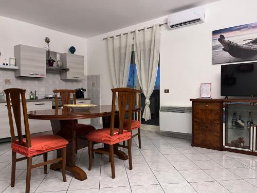Il comprend une cuisine avec une table et des chaises ainsi qu'une télévision. dans l'établissement Titina's house - Peace and nature in Fiumicino, à Fiumicino