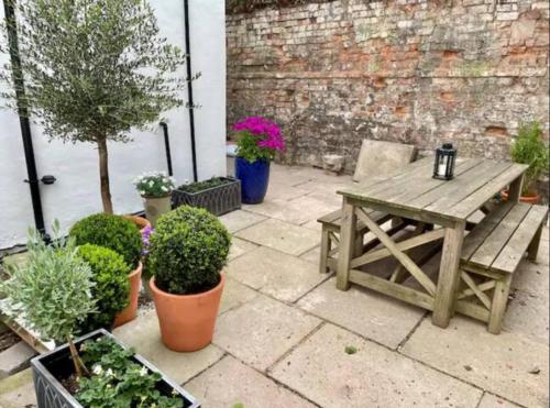 a patio with a wooden table and potted plants at Orange Rentals-Cosy Annexe, Alfresco charm in Liverpool