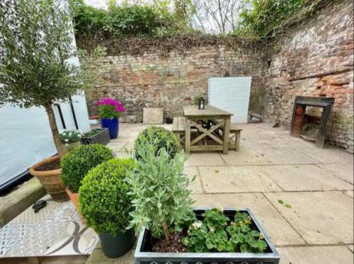 a patio with plants and a table and a brick wall at Orange Rentals-Cosy Annexe, Alfresco charm in Liverpool