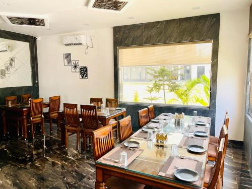 una sala da pranzo con tavoli, sedie e una finestra di Hotel Saluja Primeland a Parāsia