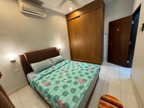 a bedroom with a bed with a green comforter at Cozy House 37 @ Alma BM in Bukit Mertajam