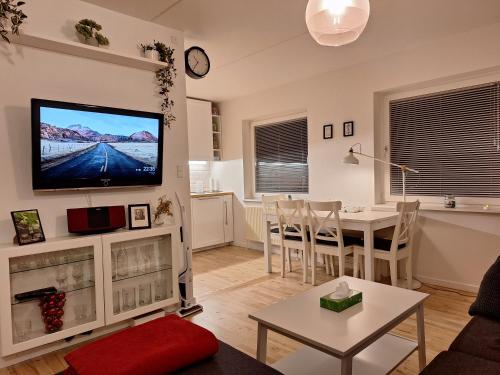 a living room with a table and a tv on a wall at Apartment Hundige in Greve